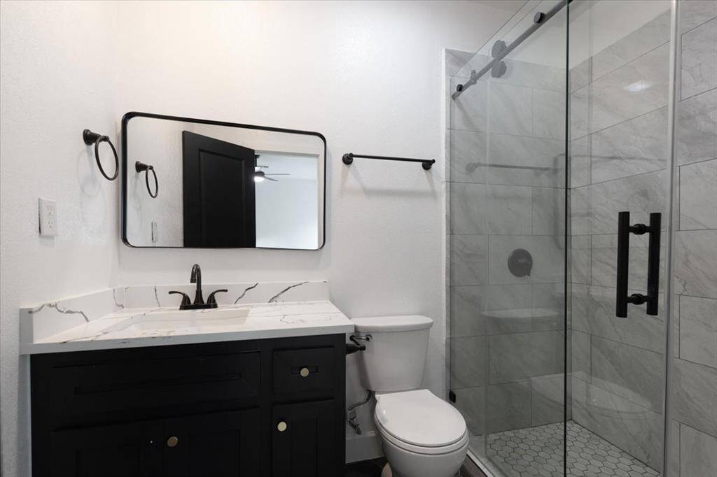 Elegant primary bathroom featuring a sleek marble vanity, spacious glass-enclosed shower, and modern fixtures.