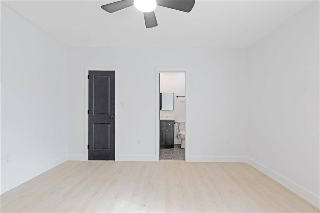 Spacious primary bedroom featuring sleek flooring, modern lighting, and an en-suite bathroom for ultimate convenience.