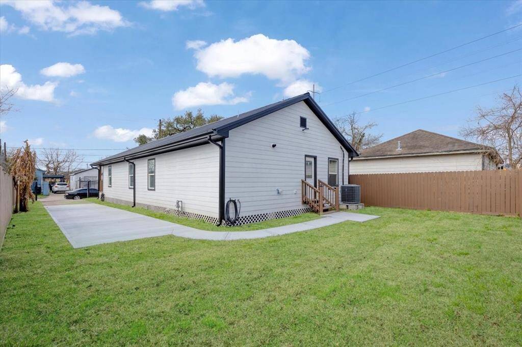 This wonderful single-story home with a modern exterior, featuring light siding and contrasting trim. It has a spacious, well-maintained yard and a concrete driveway. The property is bordered by a wooden fence, providing privacy.