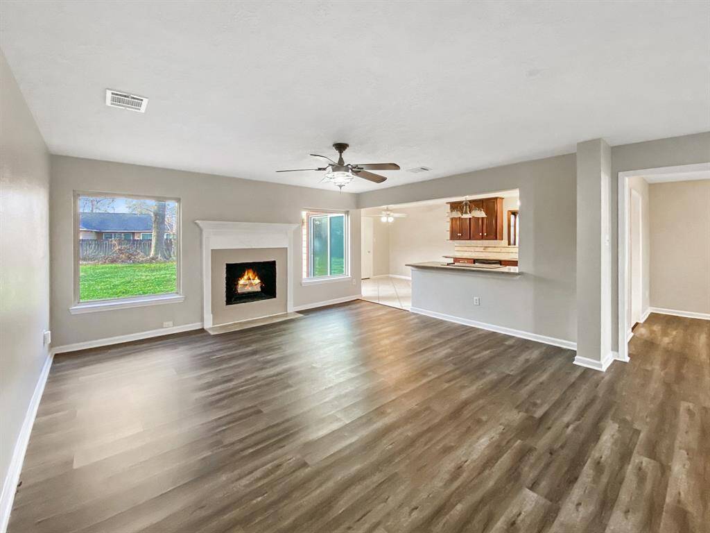 Spacious living room with two large windows, open to the kitchen and breakfast area.