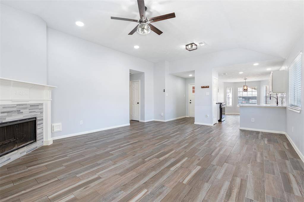 This home features a spacious, open-concept living area. It includes a stylish fireplace and ample natural light from large windows. The area seamlessly connects to a contemporary kitchen, perfect for entertaining or family gatherings.