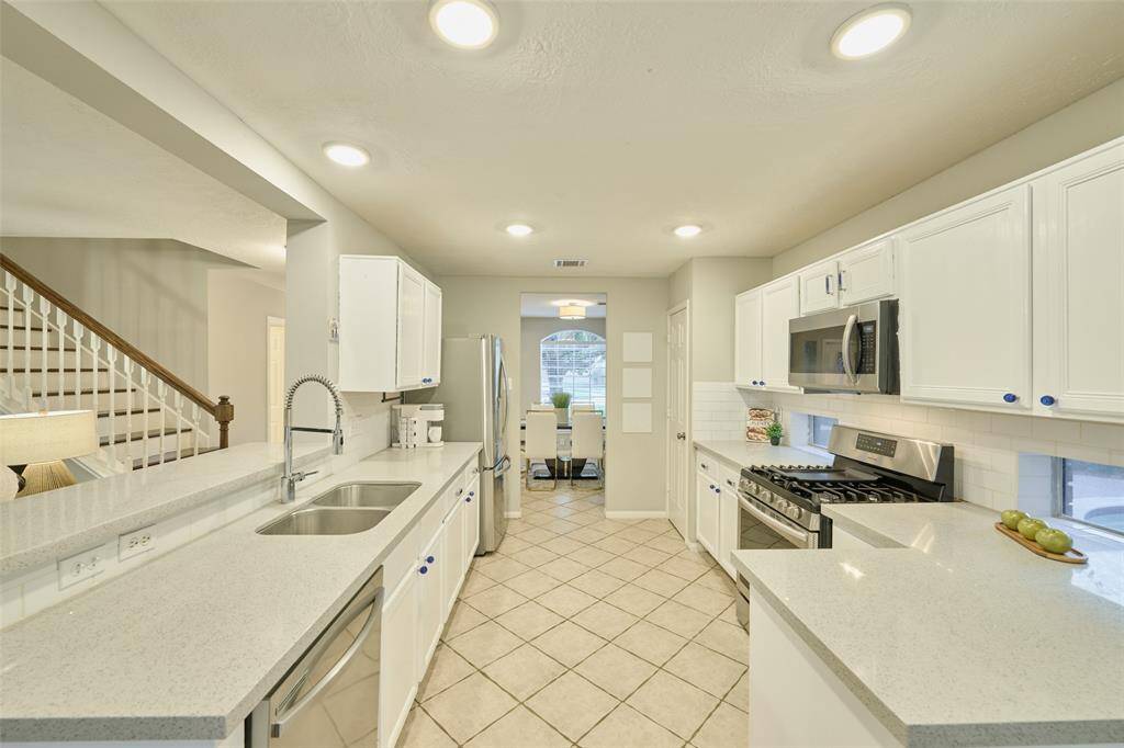 The property features stainless steel appliances, 6 burner gas range, and chic white cabinetry. There is also recessed lighting in the ceilings.