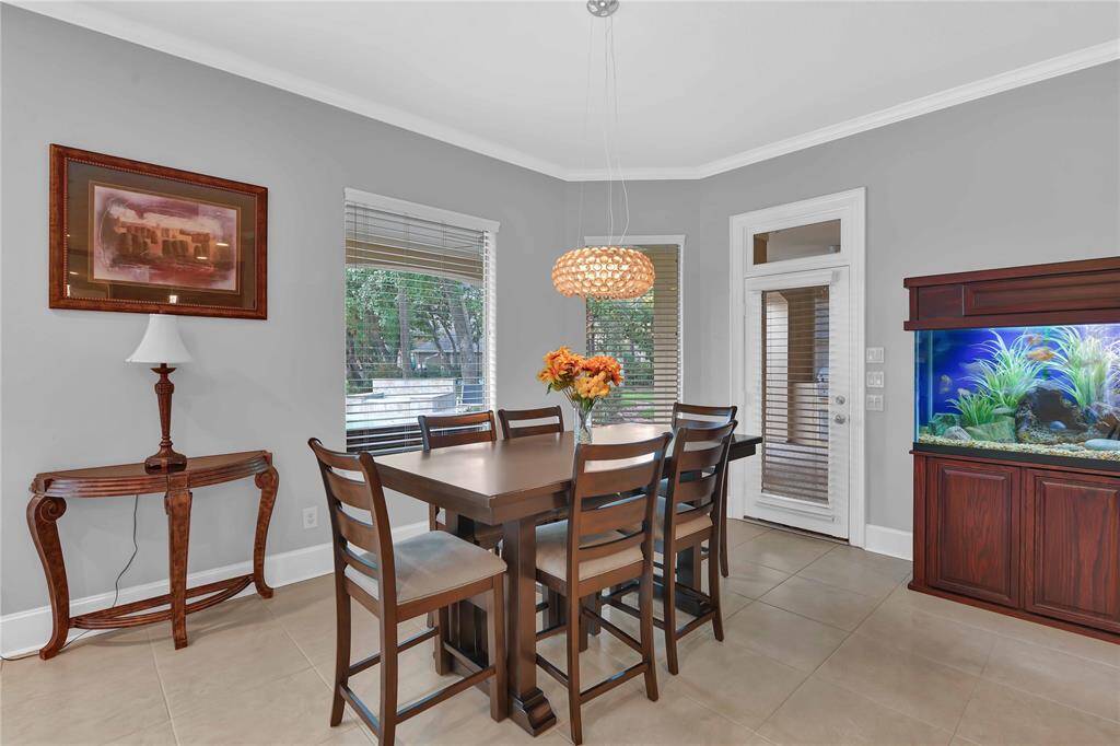 In the spacious adjoining breakfast area, large windows showcase stunning views of the backyard oasis, bathing the room in natural light & offering capOvaOng sights of the paradise outside. A chic chandelier & crown molding enhance the elegance of the space, while a door leads directly to the backyard.
