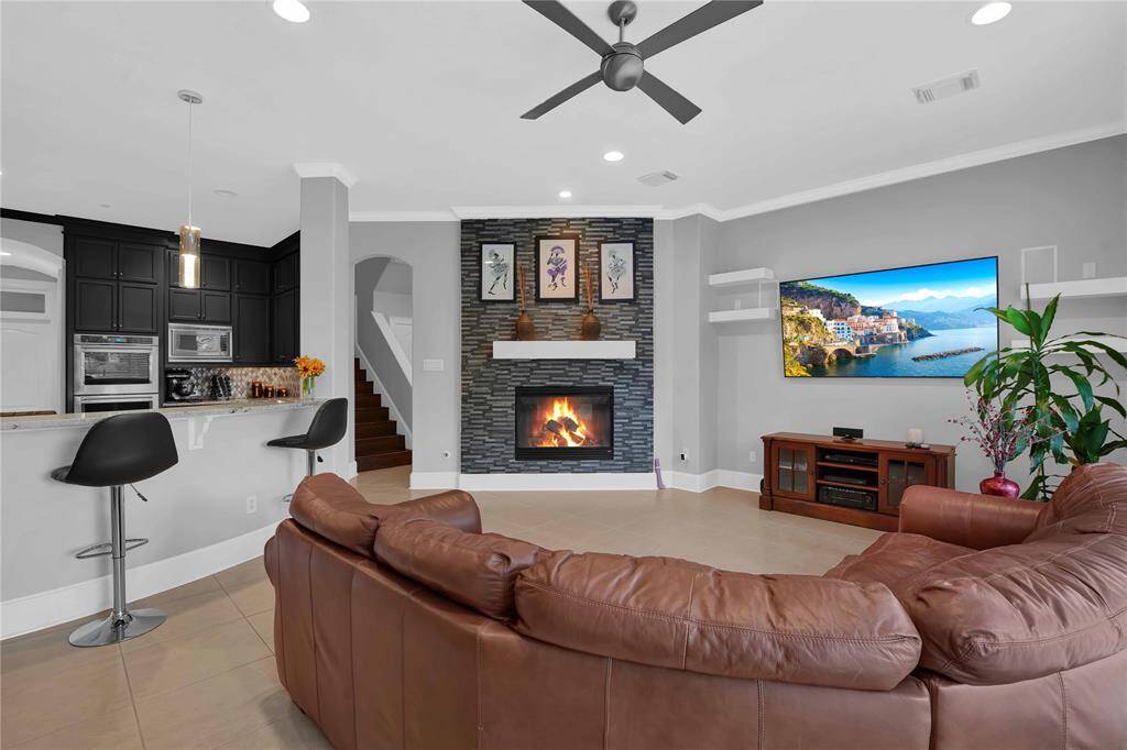 At the heart of the family room is a gas log fireplace adorned with a stunning Ole surround. The high ceiling features elegant crown molding, while a modern fan and recessed lighOng enhance the ambiance, creating a cozy yet sophisOcated atmosphere.