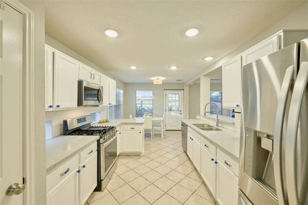 The property features stainless steel appliances, 6 burner gas range, and chic white cabinetry. There is also recessed lighting in the ceilings.