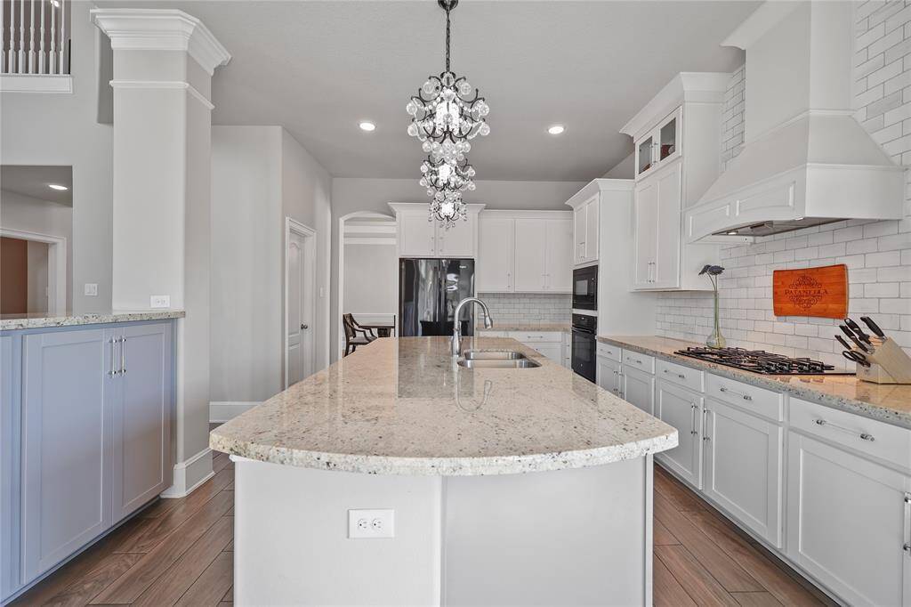 This bright and spacious kitchen features a large sink with a high-arched faucet, perfectly positioned within the granite island for convenience. To the side, a walk-in pantry offers ample storage space.