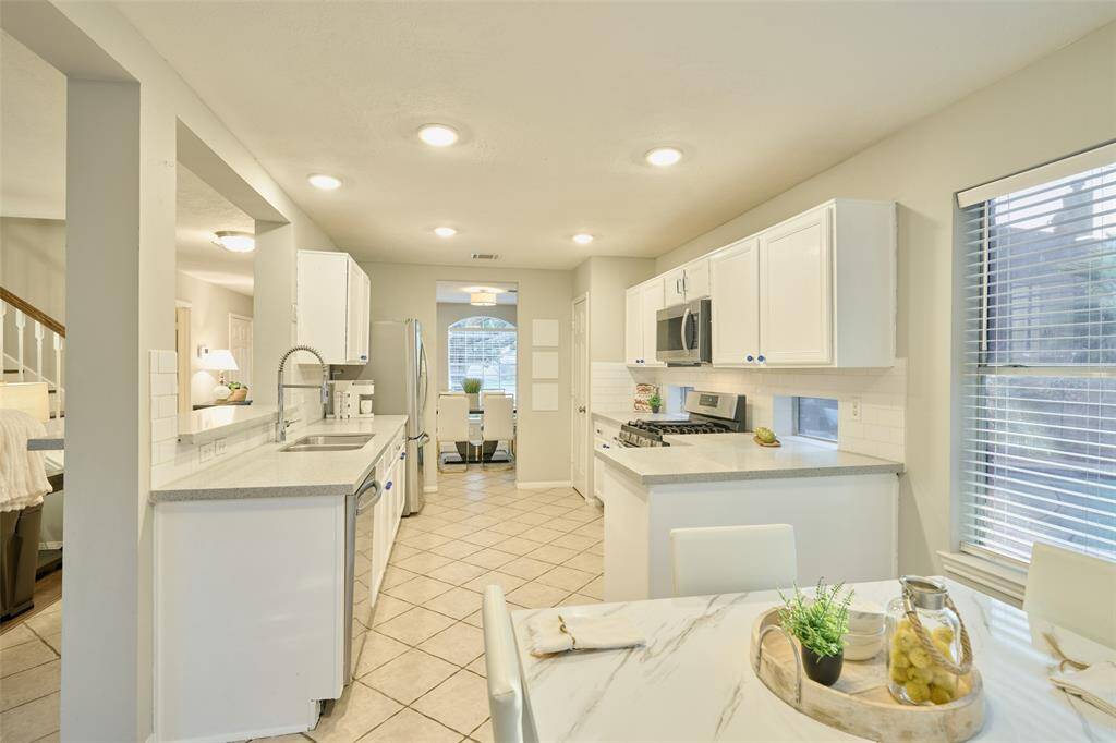 The kitchen features plenty of countertop space, subway tiled backsplash, and small picture windows beneath the cabinets that give a view of the pool.