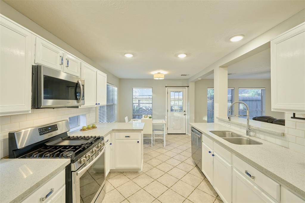 The property features stainless steel appliances, 6 burner gas range, and chic white cabinetry. There is also recessed lighting in the ceilings.