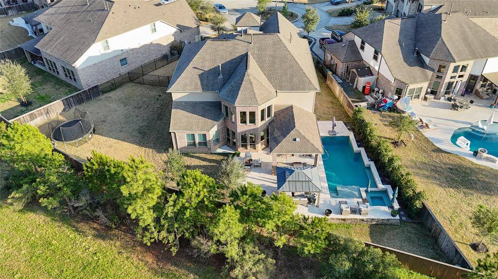 Welcome to 26 Trailing Lantana. This elevated view of the property showcases the backyard's massive size and layout. The view is enhanced with trees and shrubs for added privacy.