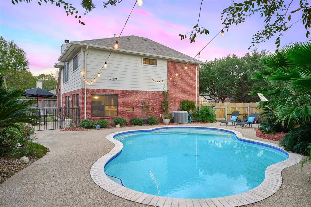 The home features a heated in-ground swimming pool, solar lighting along the fence, and a meticulously landscaped pool area.