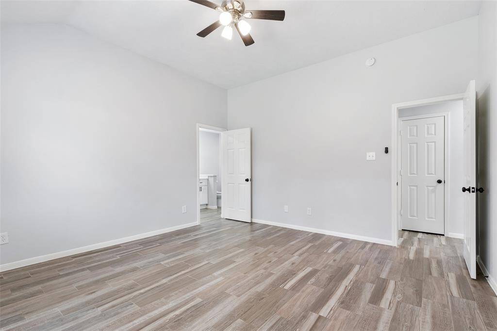 The remodeled primary bath is amazing. This bathroom features a modern design with a double vanity, white cabinetry, and sleek black fixtures. It has a large mirror, recessed lighting, and a walk-in shower with glass doors and Quartz counters. The wood-look flooring adds warmth to the space.