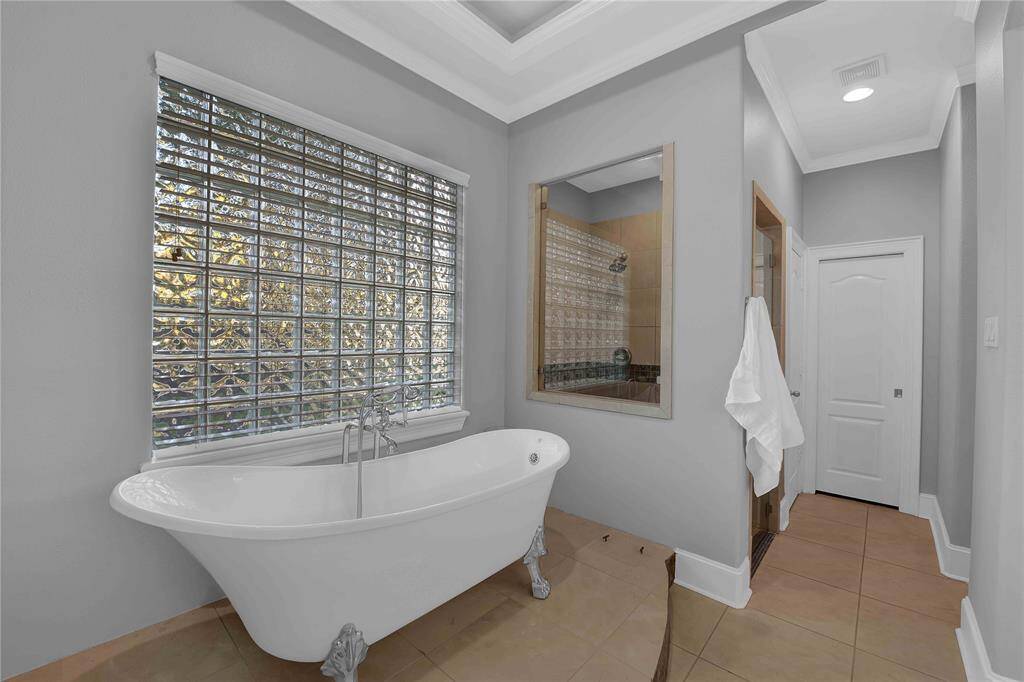 Located on the first floor, the spacious mother-in-law suite features a high tray ceiling and rich wood flooring. A wall of windows floods the room with natural light, enhancing the space's warmth and charm.