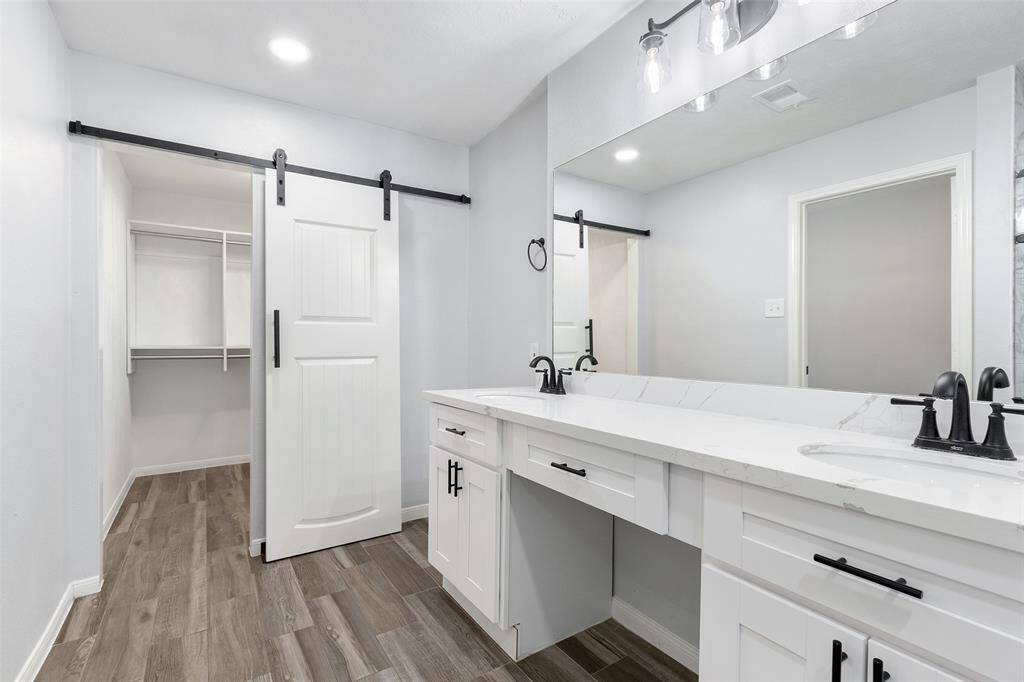 This walk-in closet features ample storage with multiple shelves and hanging rods, all in a clean, white finish. The wood-look tile flooring adds a touch of elegance. Perfect for organizing your wardrobe efficiently.