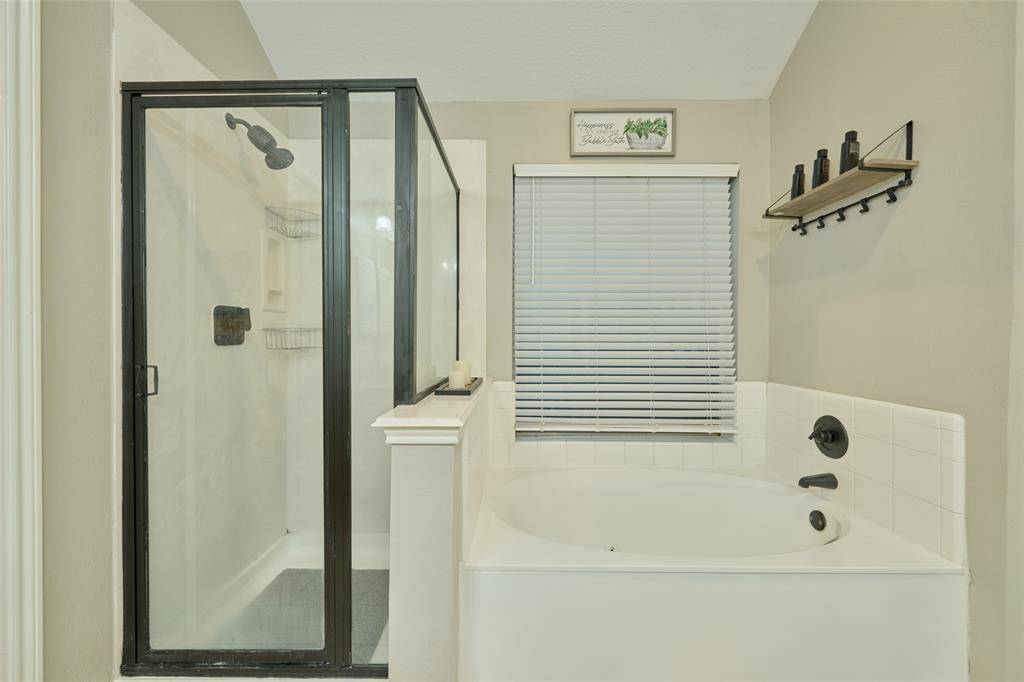 Another look at the chic framed shower doors and soaking tub. The space also features a window for natural lighting and fresh air in the bathroom.