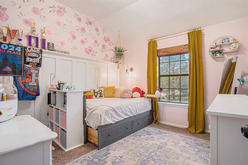 2nd bedroom features a soft pink floral accent wall, a large window with mustard curtains, and ample natural light.