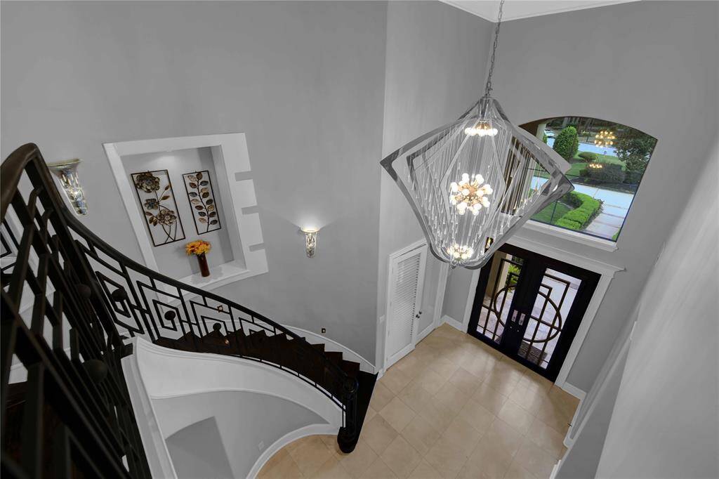 Upstairs, a spacious built-in desk overlooks the study below, providing a perfect workspace. The area features rich wood flooring and elegant crown molding.