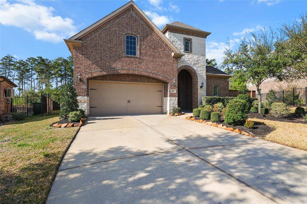 This beautiful brick-and-stone home features charming curb appeal and a well-manicured front yard with lush landscaping and mature trees in Woodlands Village Sterling Ridge.