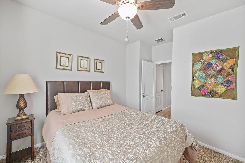 This bedroom has a neutral color palette, with soft white walls and beige carpeting, creating a warm and inviting atmosphere.