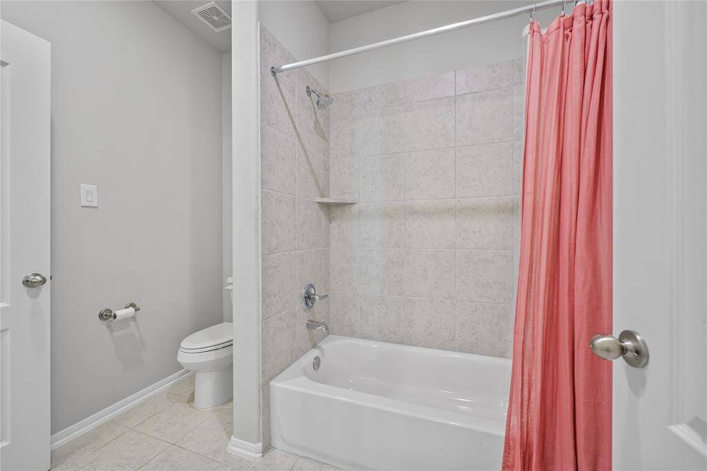 Jack and Jill tub/shower combination with a tile backsplash, and neutral toned tiled flooring.