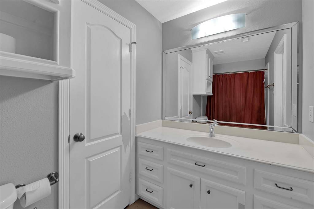 This secondary bedroom exudes warmth and comfort, featuring a high ceiling with a ceiling fan. A spacious bench stretches beneath the large bright window, allowing natural light to fill the space. Rich wood flooring adds elegance, while direct access to the bathroom provides convenience.