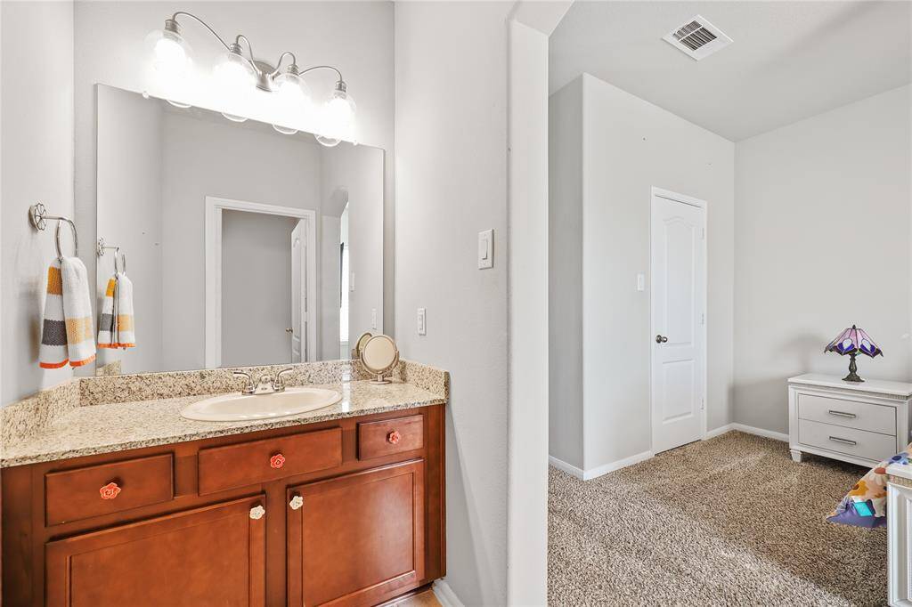 The reverse side of the  vanity area to the secondary bedroom and part of the Jack and Jill bathroom. The vanity features granite top with wooden drawer and cabinet area for storage.