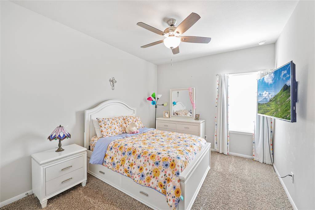 The third bedroom with the same neutral color palette, beige carpeting and ceiling fan.
