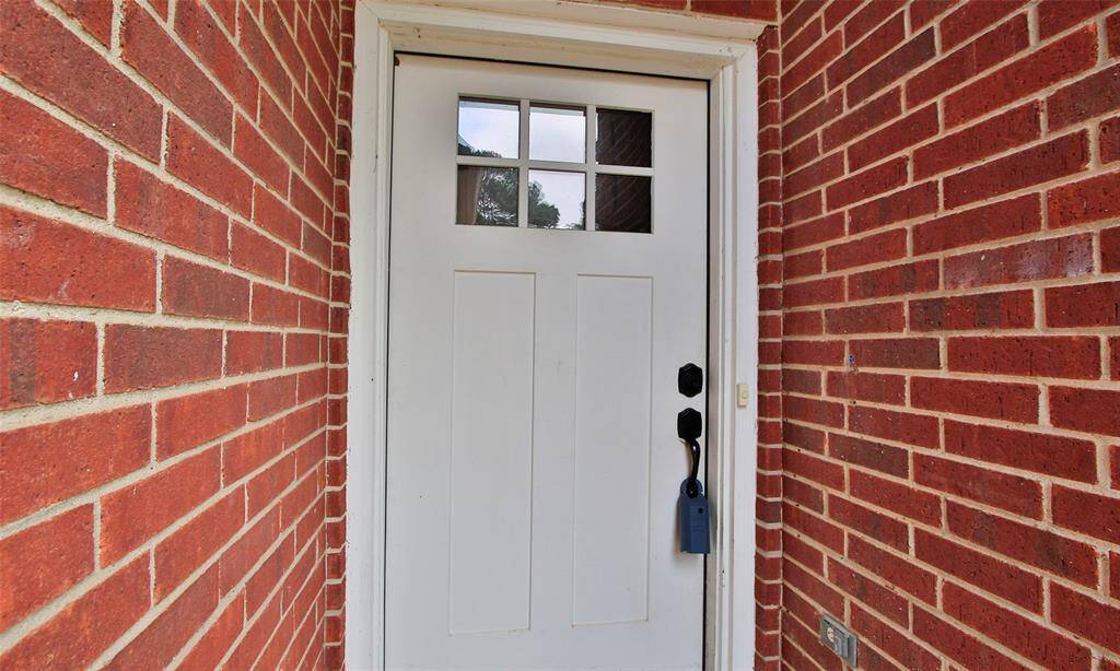 This photo shows a welcoming front door with a classic white finish. The door features a small window pane design and modern black hardware, offering a stylish entrance to the home.