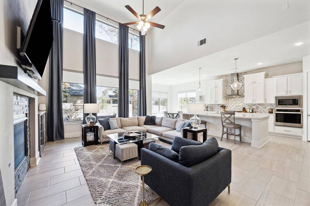 Yet another view of the family room which the large windows looking out to the backyard. You can also see the breakfast area which has plenty of lighting as well! The blinds are motorized and these curtains will remain with the house!