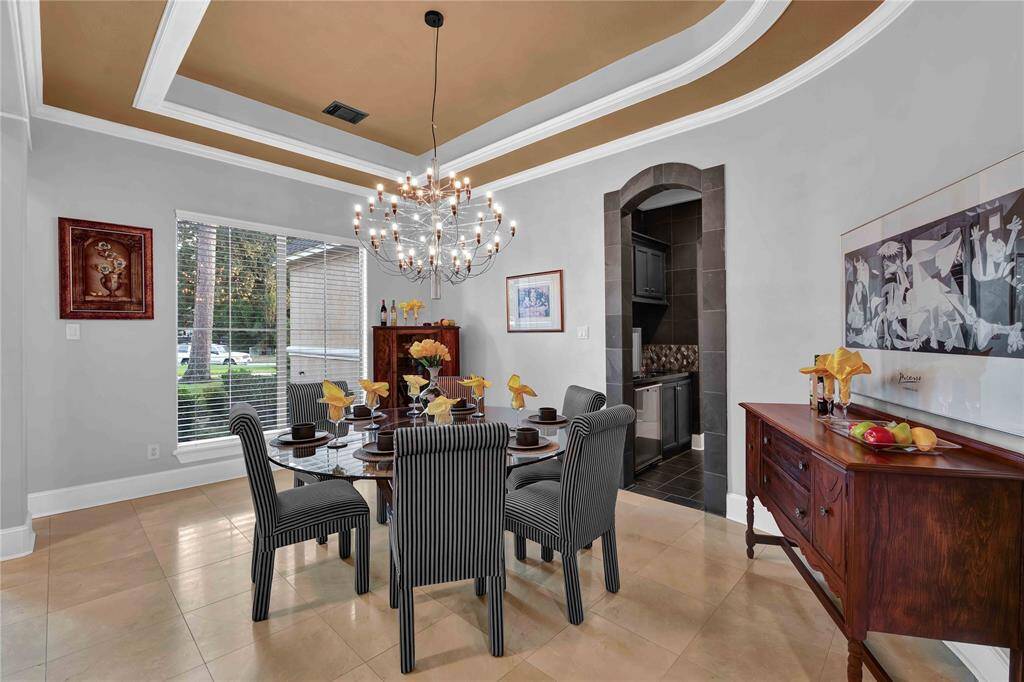 The formal dining room offers a high tray ceiling with crown molding and an elegant chandelier as its centerpiece. Natural light streams in through large windows fi?ed with 2-inch blinds, creaOng a bright and welcoming atmosphere for sophisOcated gatherings.
