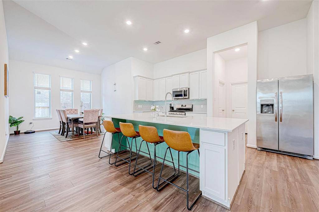 Kitchen features stainless steel appliances, sleek quartz countertops, and a large island.
