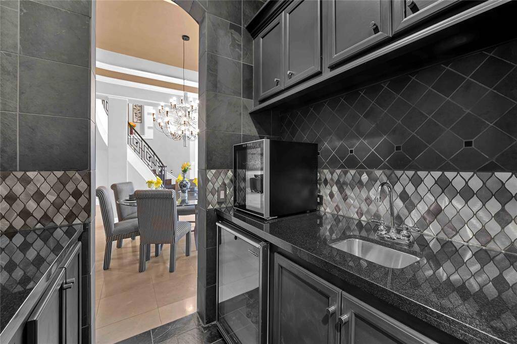 Don’t miss the butler’s pantry/wet bar, featuring ample countertop space, cabinets, and a wine fridge for convenient entertaining. Gleaming granite countertops and an elegant Ole backsplash complement the design.