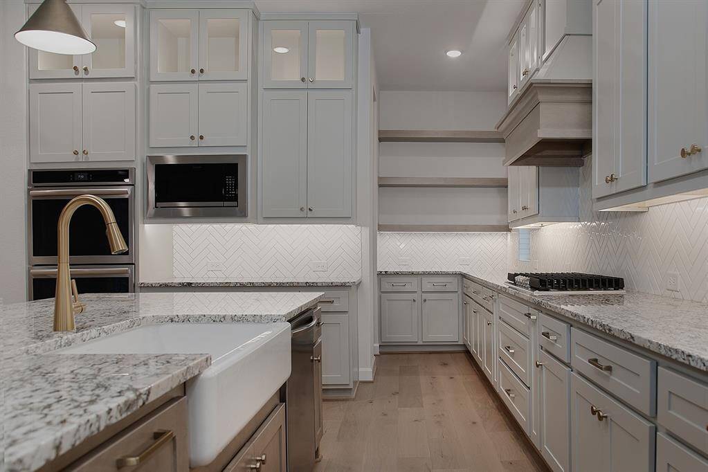 Upgraded appliances include a 36" gas cooktop, vent hood, microwave, double ovens and dishwasher