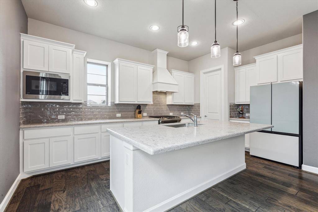 The kitchen boasts quartz countertops and features an open island. This design offers both style and functionality, providing plenty of space for meal preparation and casual dining. The open island serves as a central hub, perfect for entertaining guests or enjoying family meals, and enhances the overall flow of the kitchen.