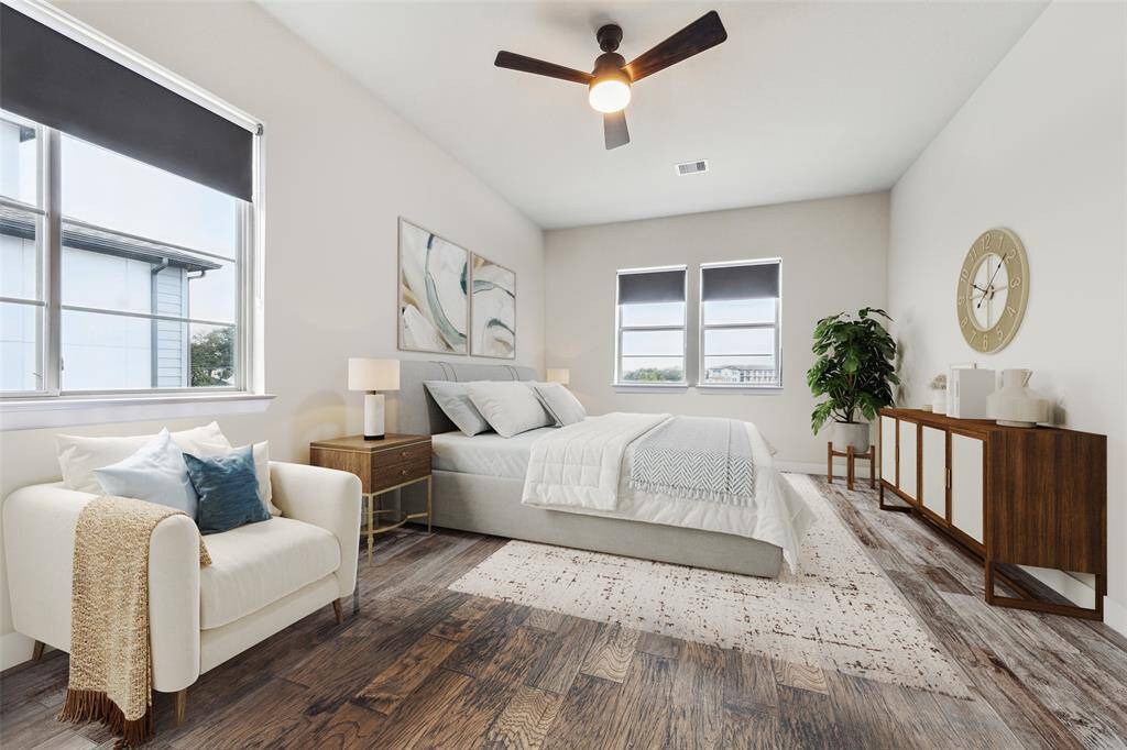 The primary bedroom offers a generous amount of space and features ample natural light. It includes stylish window treatments and is equipped with a modern 3-blade ceiling fan, creating a comfortable and airy environment. (Digitally Staged)