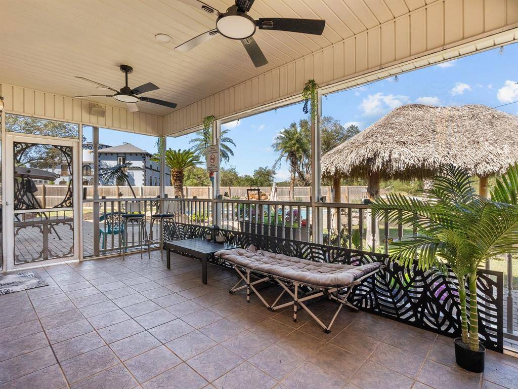 Discover your own tranquil retreat in this inviting screened patio, complete with cool tile flooring and breezy ceiling fans. Lounge in comfort while enjoying the picturesque backyard oasis and its quaint tiki hut—perfect for serene outdoor living.