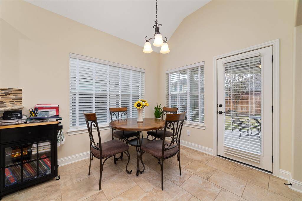 The bright and airy breakfast room is surrounded by large windows, offering scenic views of the backyard and covered porch.