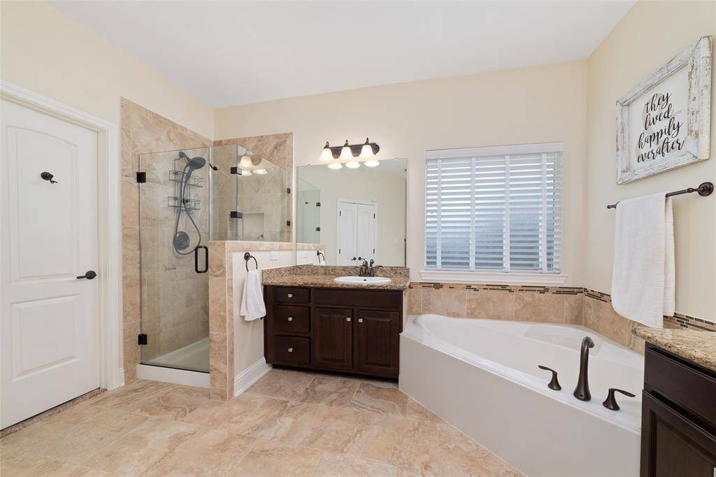 A frameless glass shower and granite countertops add spa-like luxury to the ensuite bathroom.