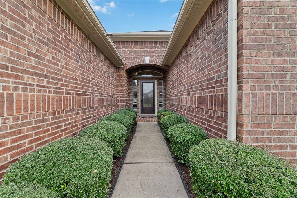 A gorgeous topiary-lined walkway leads gracefully to the front door, offering a grand and inviting entrance.