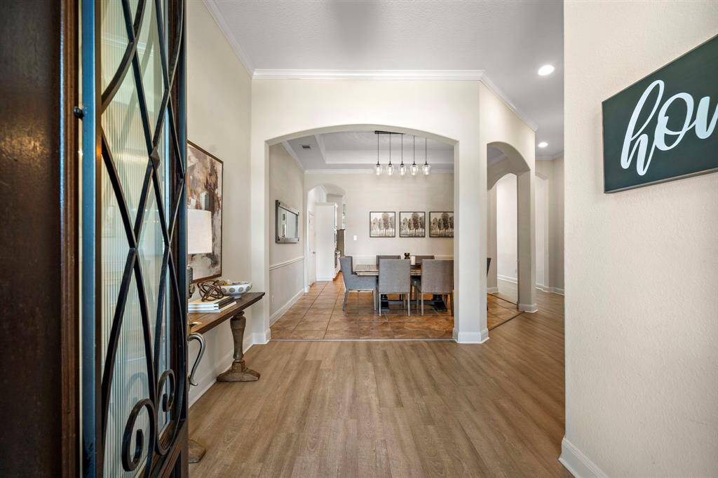 Step into the welcoming entryway featuring a covered archway that flows effortlessly into entertainment areas. The formal dining room, showcasing abundant natural light and tile flooring, offers ample space for hosting with its open layout and sophisticated elegance. This area sets the tone for the home's graceful interior design.