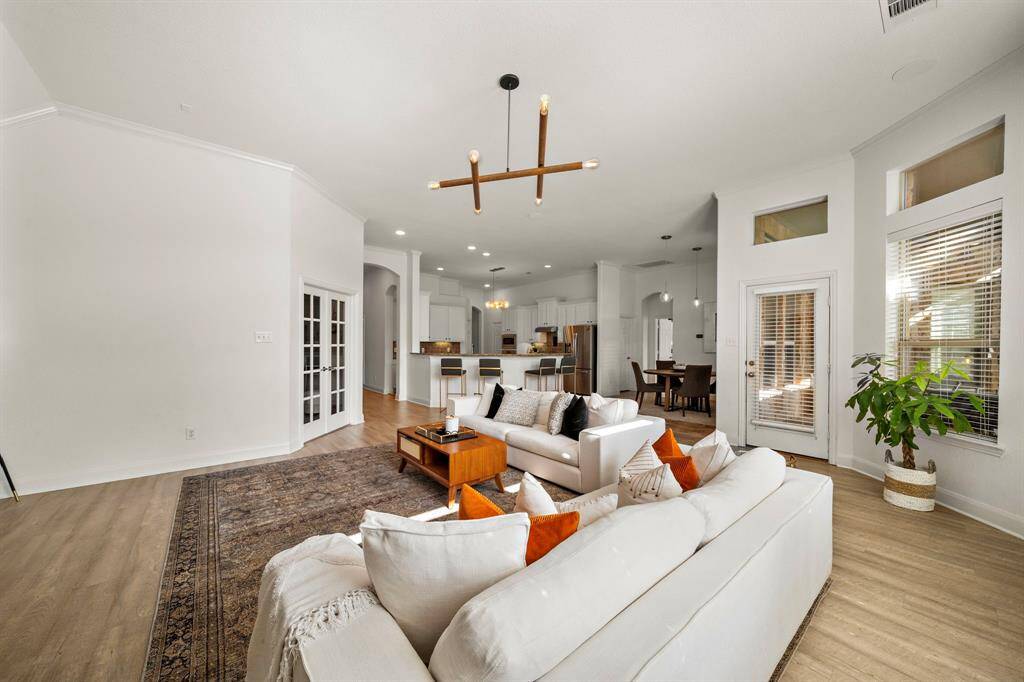 The expansive living room offers an ideal setting for gatherings, featuring abundant natural light, a cozy fireplace, and patio access for seamless indoor-outdoor living. With a modern open layout, ample seating space, and designer lighting, this area combines functionality with elegance.
