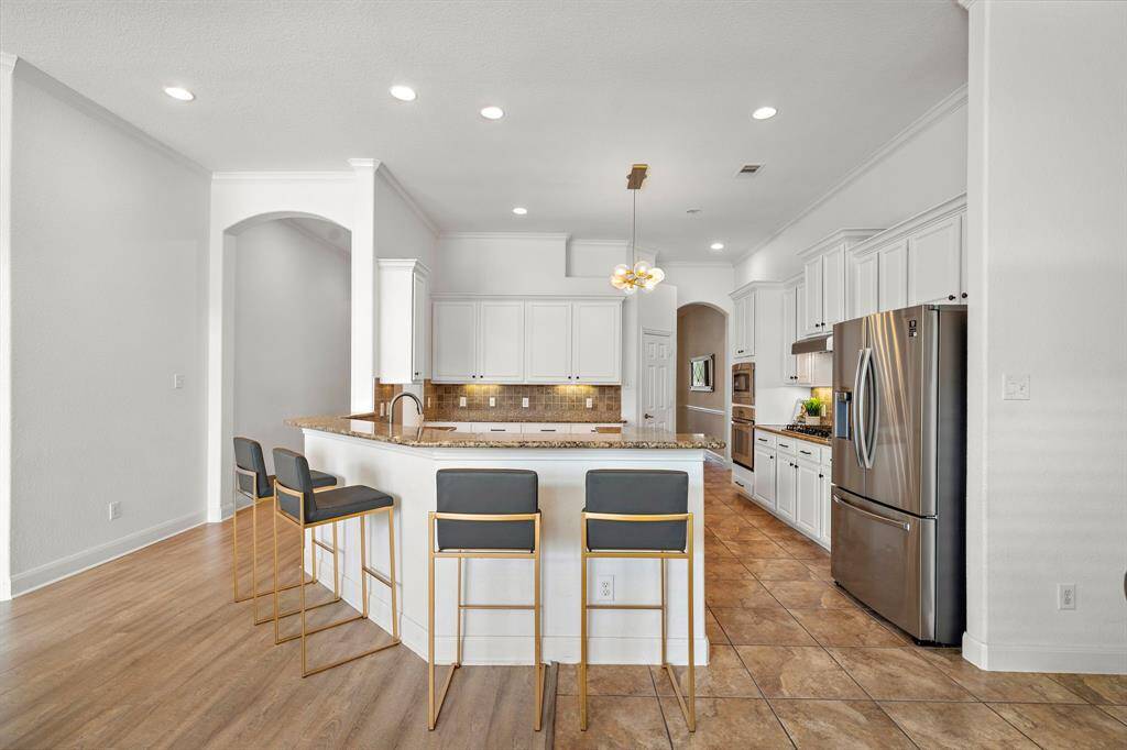 The kitchen impresses with elegant granite countertops, ample stainless steel appliances, and a spacious walk-in pantry. Featuring expansive cabinetry and a breakfast bar, it offers a blend of modern convenience and comfort. Ideal for culinary endeavors, this space is both functional and inviting.