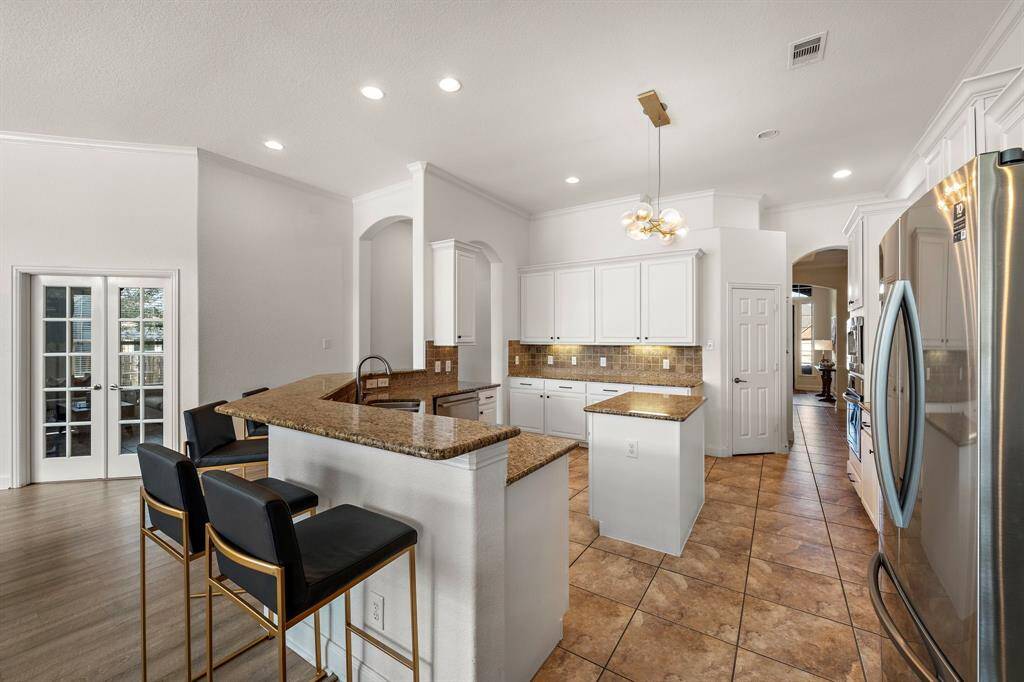 Expansive kitchen boasts granite countertops and stainless steel appliances, enhancing functionality and style. The breakfast bar and island provide ample space for dining and preparation, while the abundant cabinetry and walk-in pantry ensure organized storage. An adjacent breakfast area flooded with natural light creates a seamless, welcoming space for casual meals.