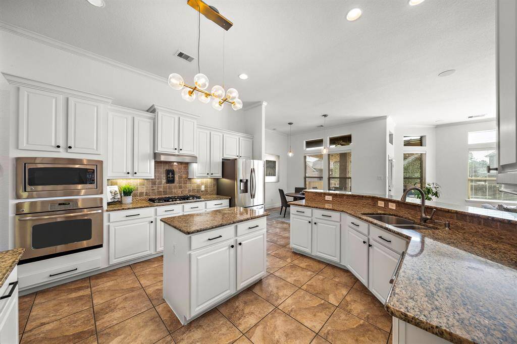 Experience culinary delight in this kitchen, boasting granite countertops and stainless steel appliances. Expansive cabinetry and a central island enhance functionality, while the breakfast bar invites casual dining. The open layout provides seamless flow to the naturally lit breakfast area and living spaces.