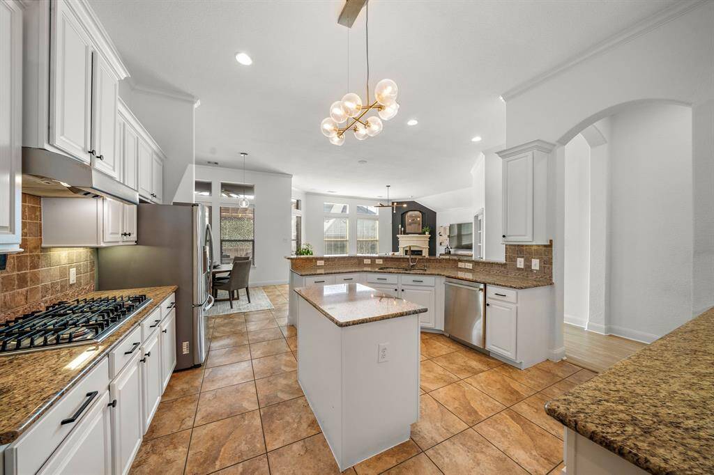 The kitchen combines style and functionality with granite countertops, stainless steel appliances, and expansive cabinetry. A central island enhances preparation space, while the breakfast bar offers casual dining. Its open layout seamlessly connects to the living area and naturally lit breakfast space, creating a welcoming atmosphere for culinary endeavors.