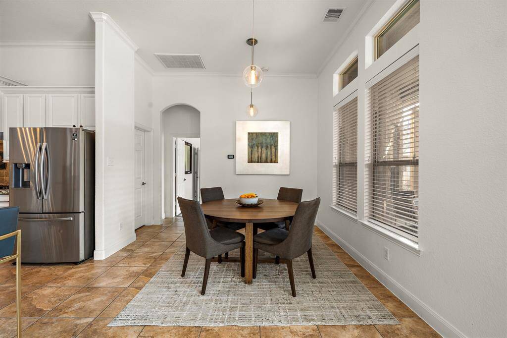 The breakfast area offers a delightful space for casual dining, perfectly positioned to capture abundant natural light through oversized windows. Open to the living room and kitchen, this inviting space features tile flooring and modern lighting, creating a seamless flow for everyday meals and gatherings.