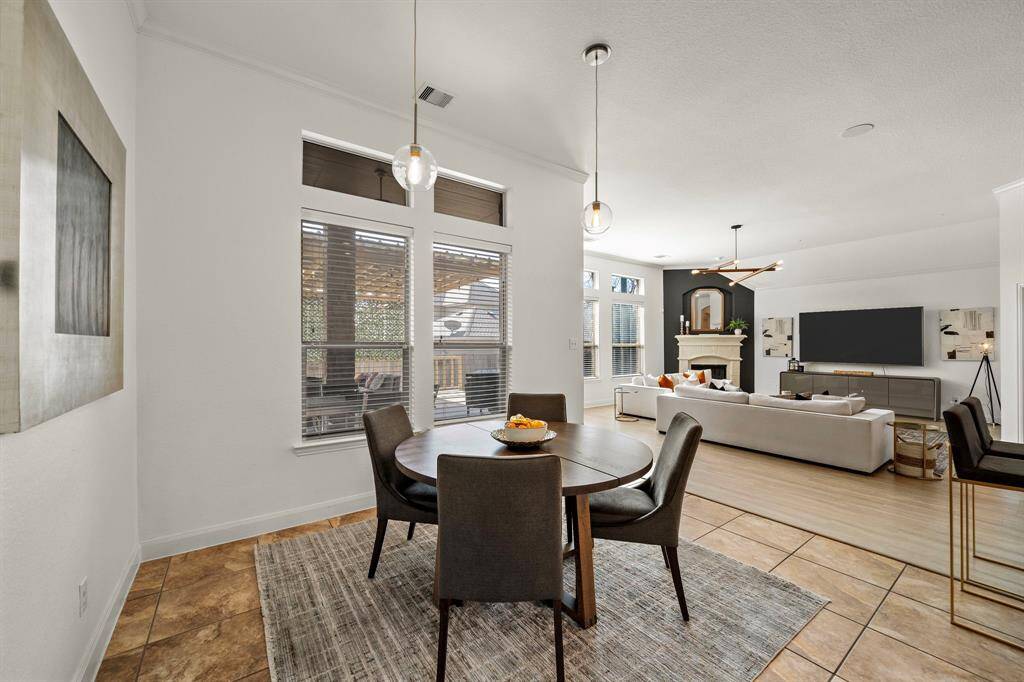 Open breakfast area near the kitchen offers a casual dining space with tile flooring. Natural light floods through oversized windows, while pendant lighting fixtures illuminate the space.