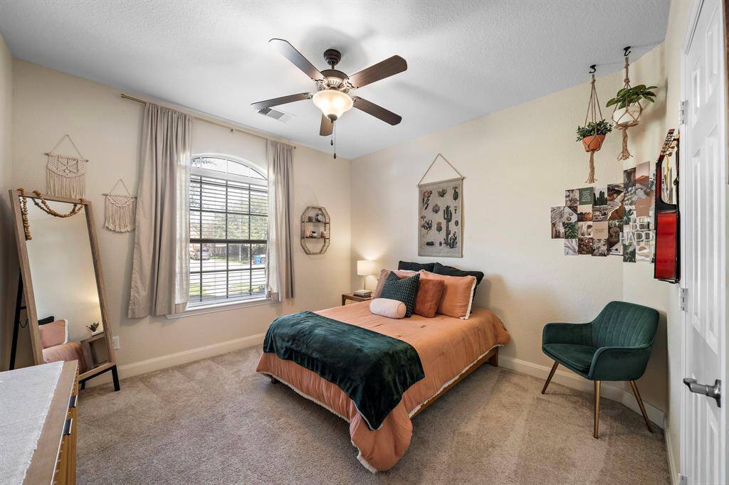 This cozy bedroom offers a restful retreat with large windows providing abundant natural light. Soft tones and plush carpeting enhance its welcoming atmosphere, making it an ideal space for relaxation or personalized decor.