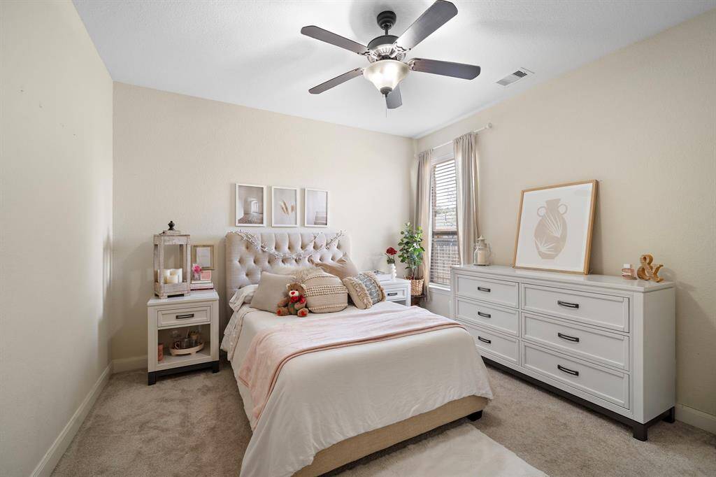 This cozy bedroom offers a serene retreat with soft tones and plush carpeting. Large windows fill the space with natural light, creating a warm and inviting atmosphere ideal for relaxation or personalization.