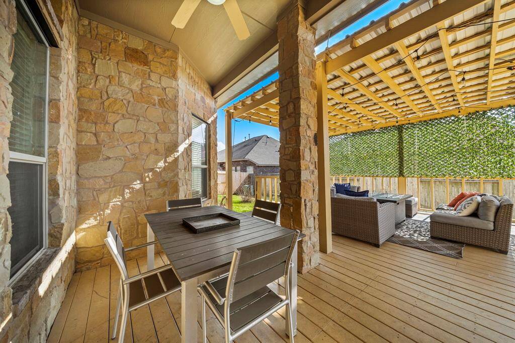 Experience serene outdoor living on the spacious covered patio, featuring a pergola and seating area ideal for entertaining. Enjoy the blend of wood decking and stone accents, creating a welcoming extension of the home that invites relaxation in a private setting.