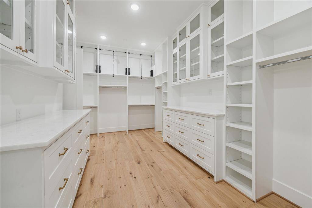 An outstanding primary closet. Adjustable shelving, pull-down rod systems, glass-front cabinetry and an abundance of drawers to make this space the ultimate in organization and enjoyment in personal space. The primary closet also offers access to the second floor laundry room. You will love all the special details in this home.